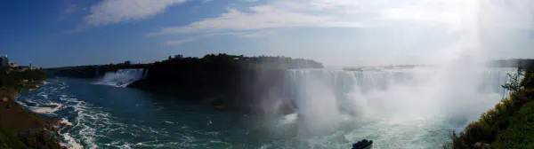 Panoramic view of Niagara Falls with Rainbow Bridge at the left. The left falls are the American Falls and the Bridal Veil Falls, to the right the Horseshoe Falls.